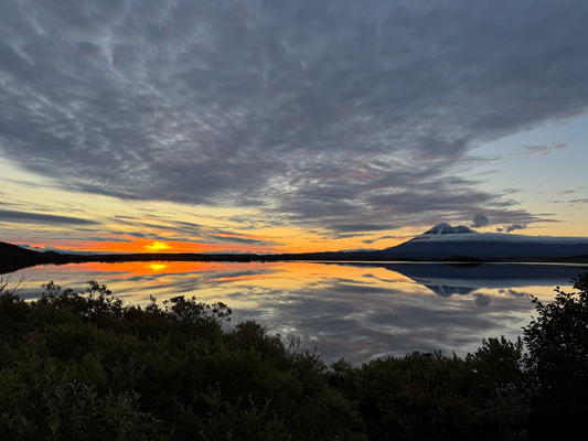 Lake VIew with Sun setting in the horizon and a mountain to the right